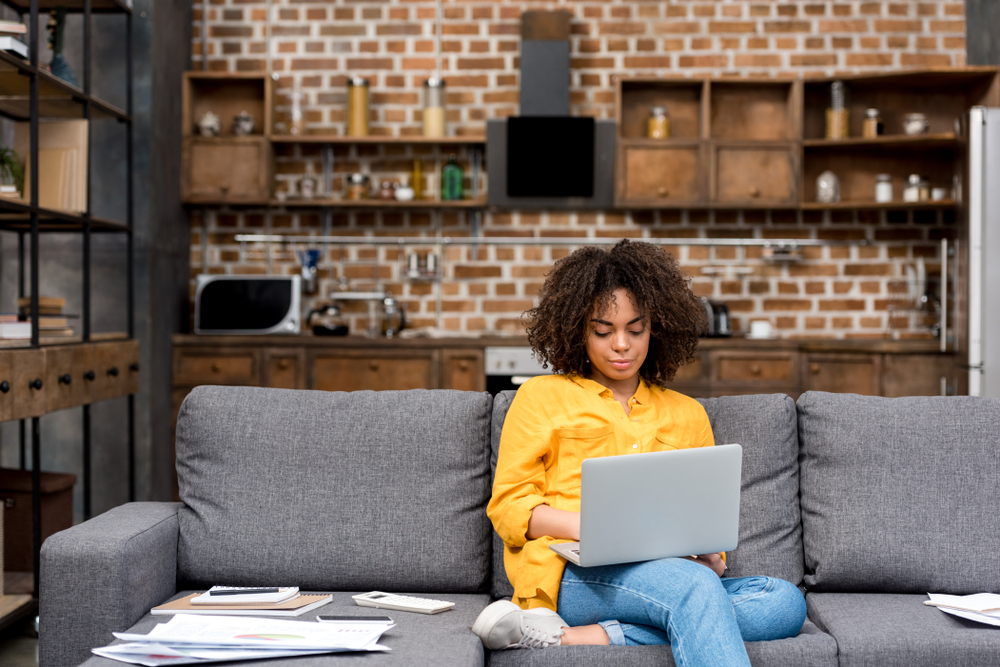 person working on a laptop while sitting on a couch 