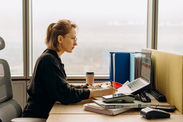 Female management accountant sitting at a laptop in front of a window wanting to know how to become a cma 