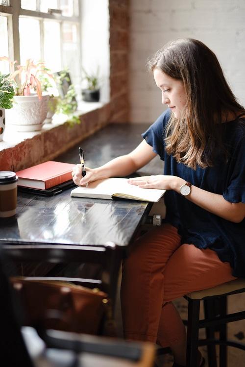 woman working on a desk with a piece book and pen