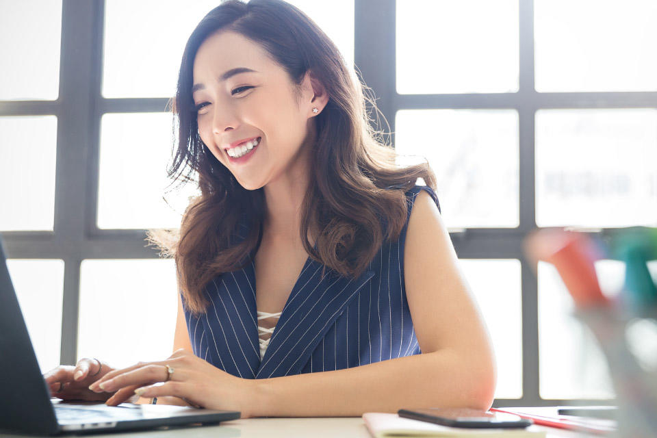 Student in front of laptop typing and smiling 