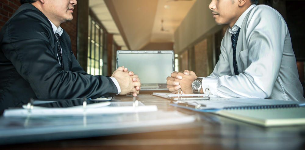 Negotiation of two statesman with clasped hands in office. Two men's hand on a desk. Negotiating business concept.