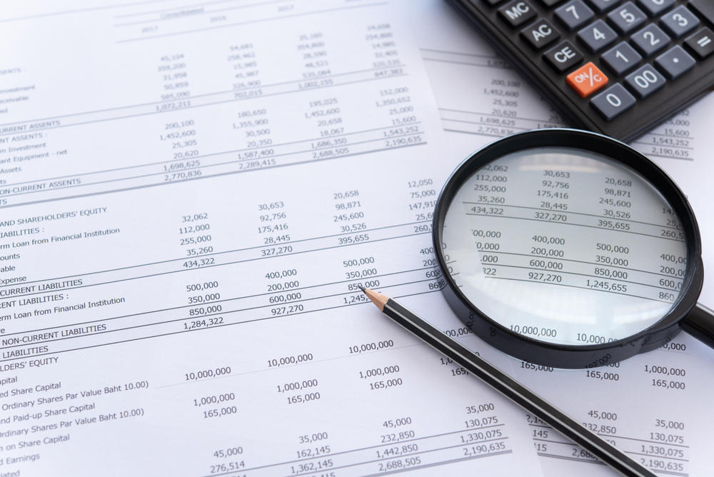 accounting audit concept. calculator and magnifying glass on financial statement and balance sheet annual on auditor's desk.