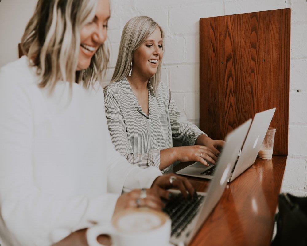 two women working on laptops