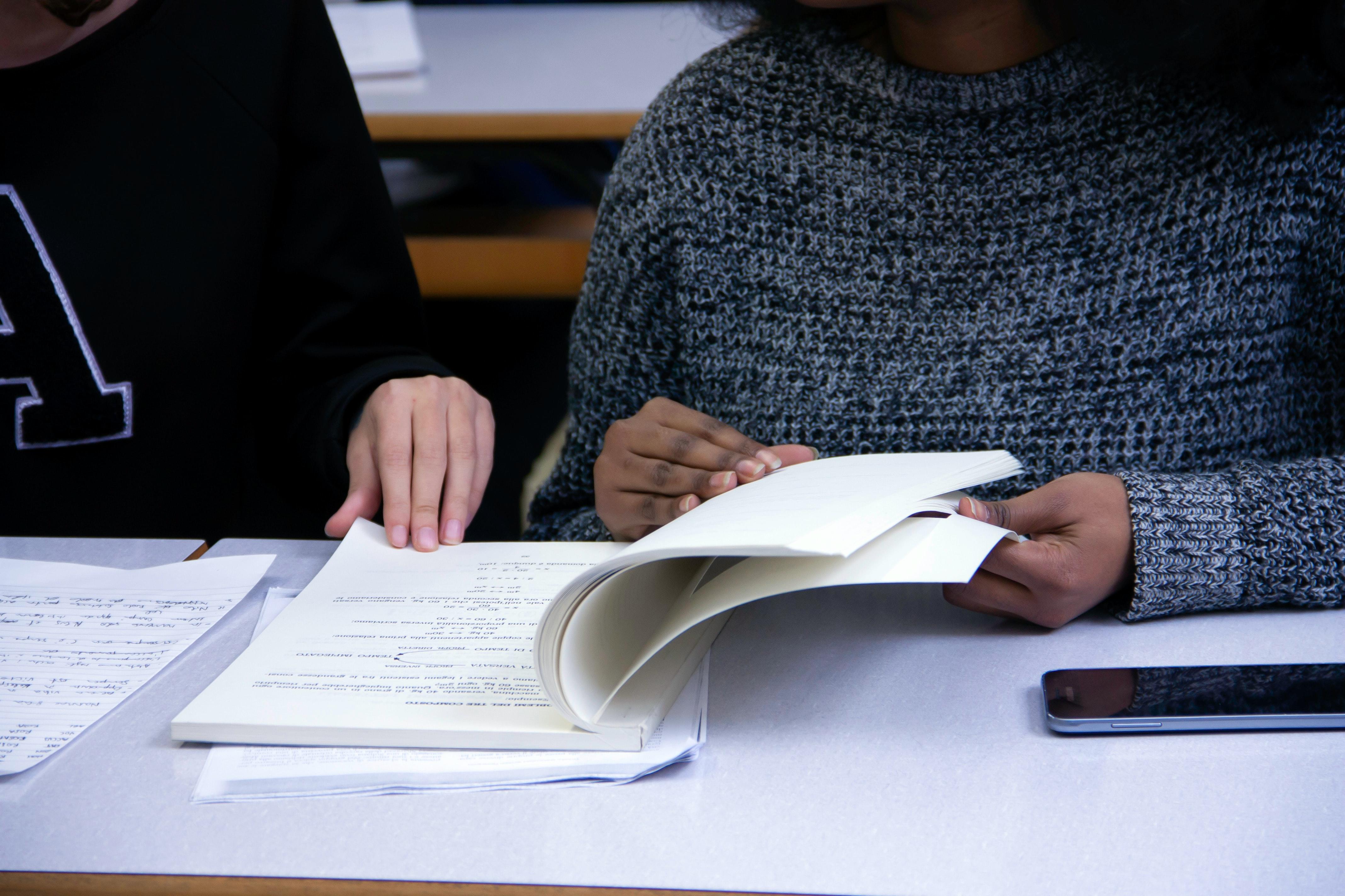 two people studying a textbook