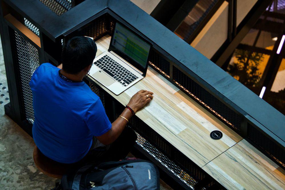 man typing on laptop in a library