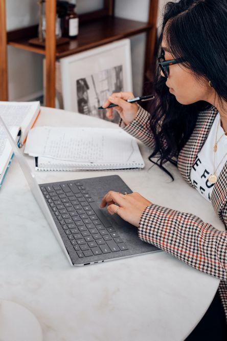 person studying on laptop and writing in notebook