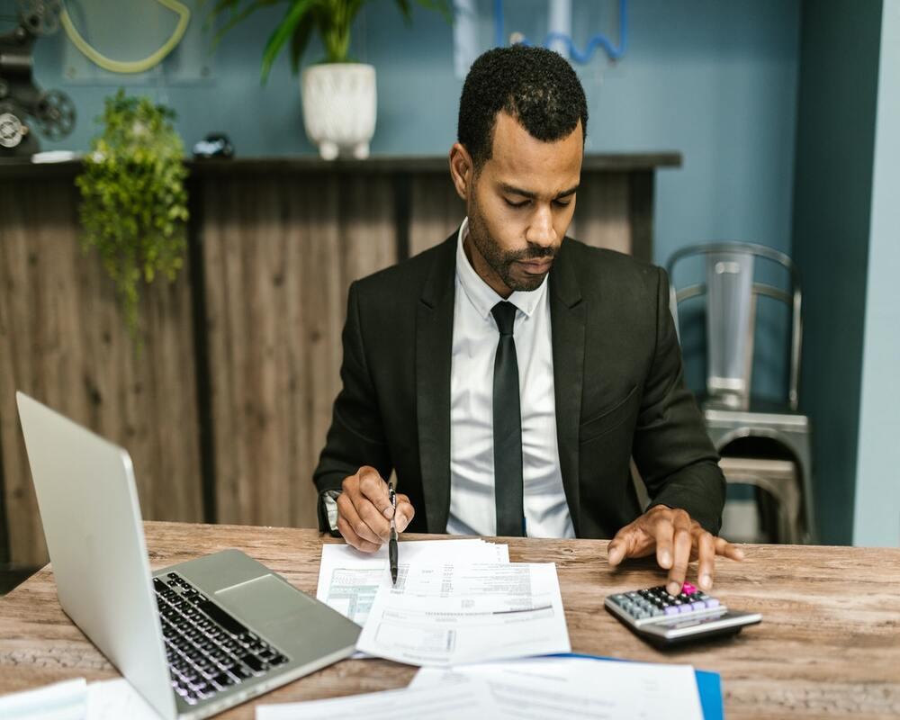 man in black suit jacket holding pen and paper