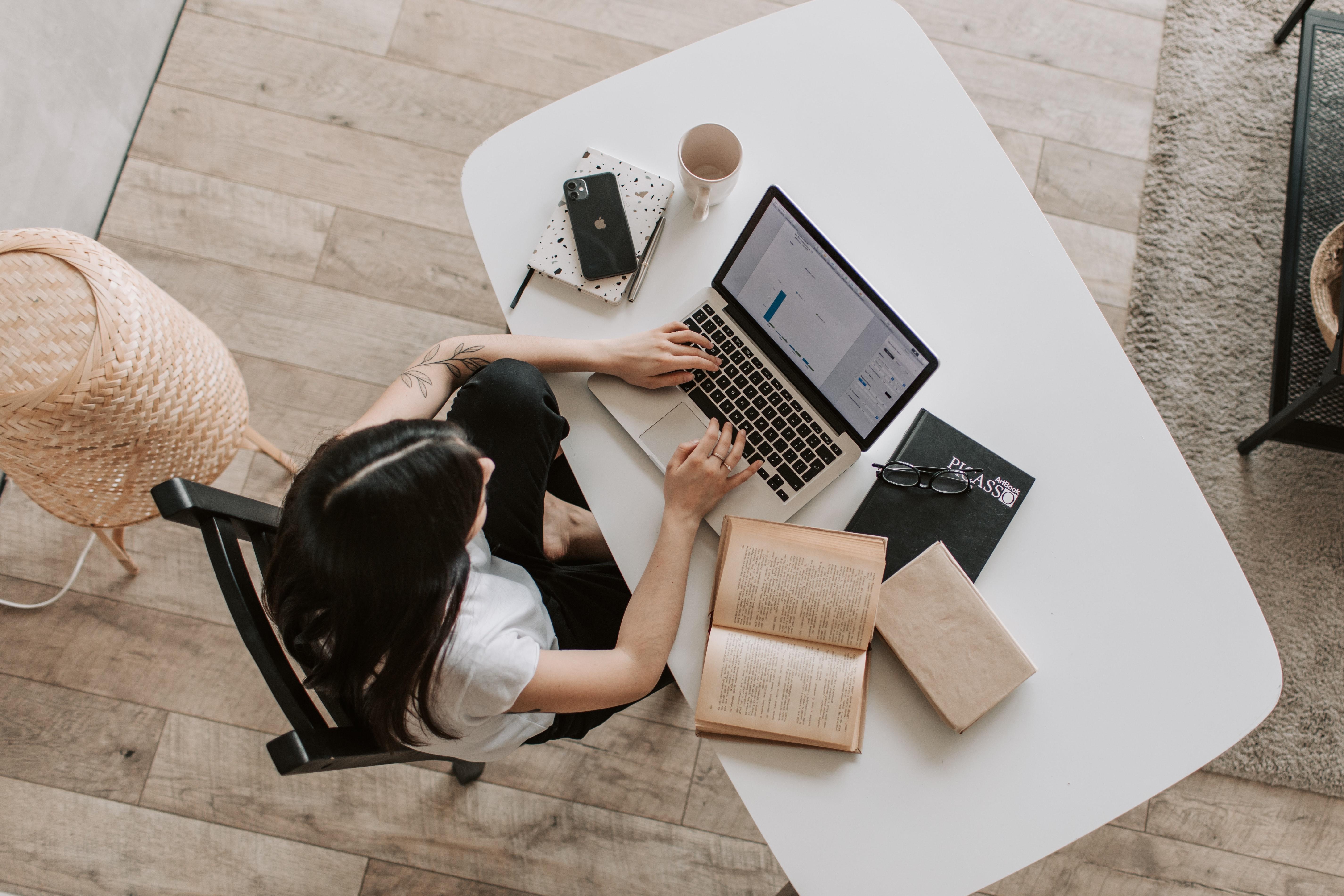 Woman in front of a desk with computer and notebooks