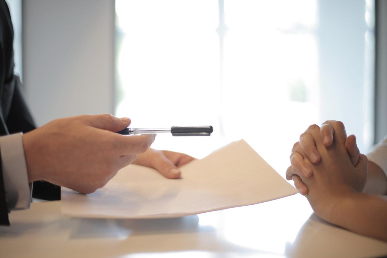 A paper being passed to someone to sign