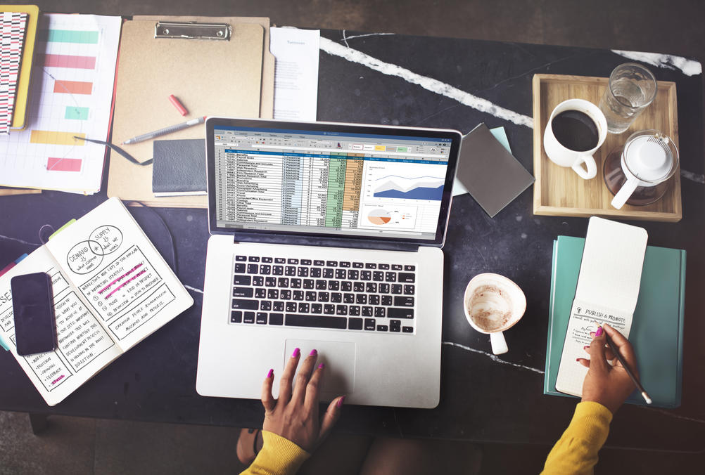 person studying on a laptop and writing in notebook