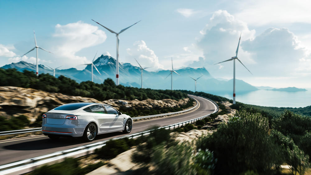 electric vehicle driving down a road with windmills