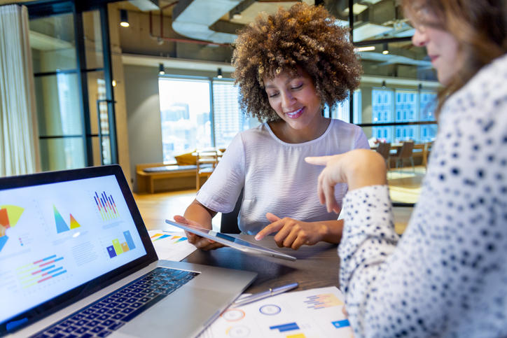 two colleagues reviewing charts on a laptop