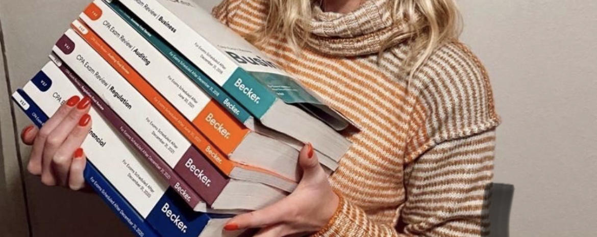 person holding becker cpa textbooks