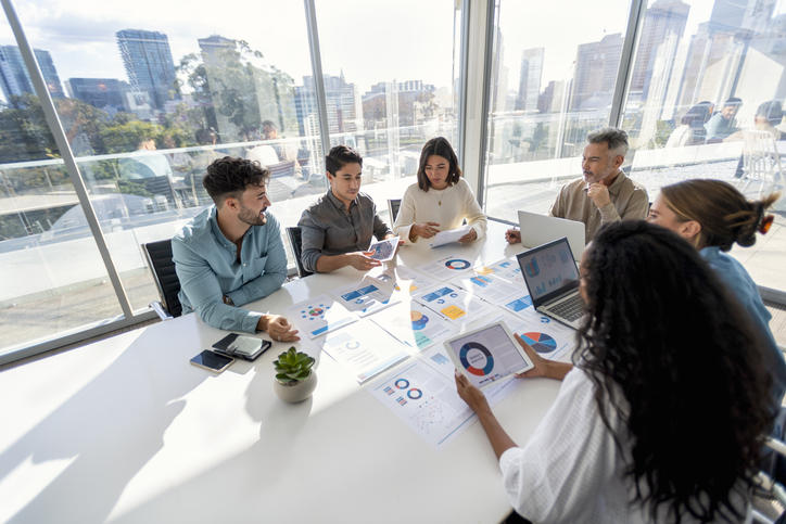 group of colleagues huddling over charts and graphs