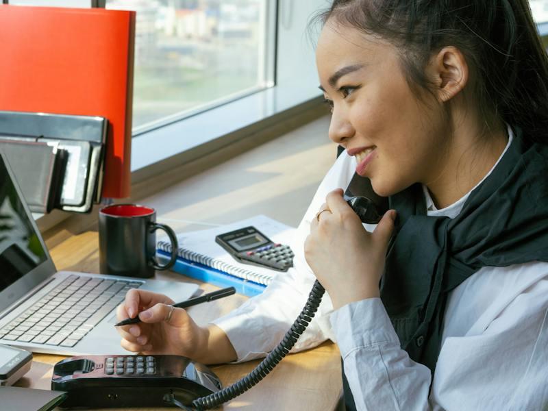 An Asian woman who is an International Certified Management Accountant talking on the phone and smiling