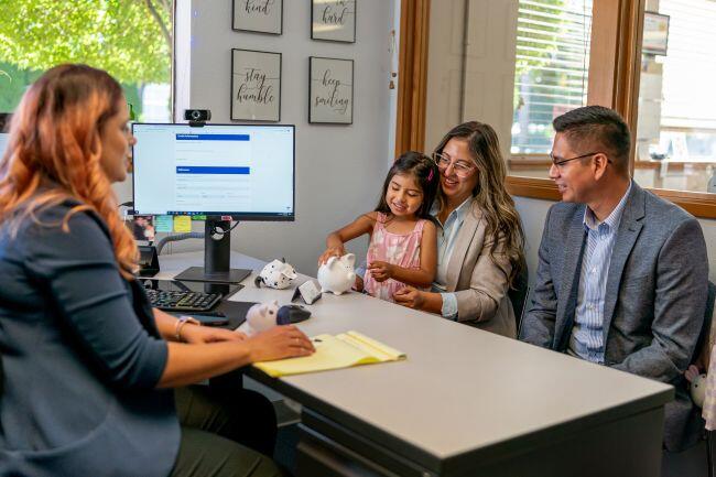An accountant sitting with a young family discussing trump account tax implications