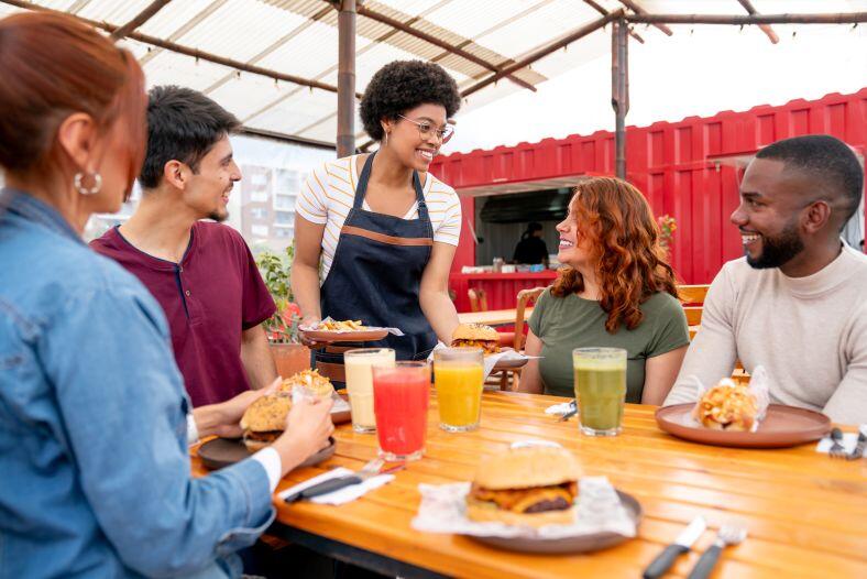 Young woman waiting tables at an outdoor restaurant and happy to be eligible for the no tax on tips provision