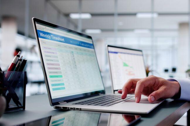 Closeup of a laptop - the screen says "weekly timecard" with a spreadsheet on it. This represents hourly workers and the no tax on overtime provision