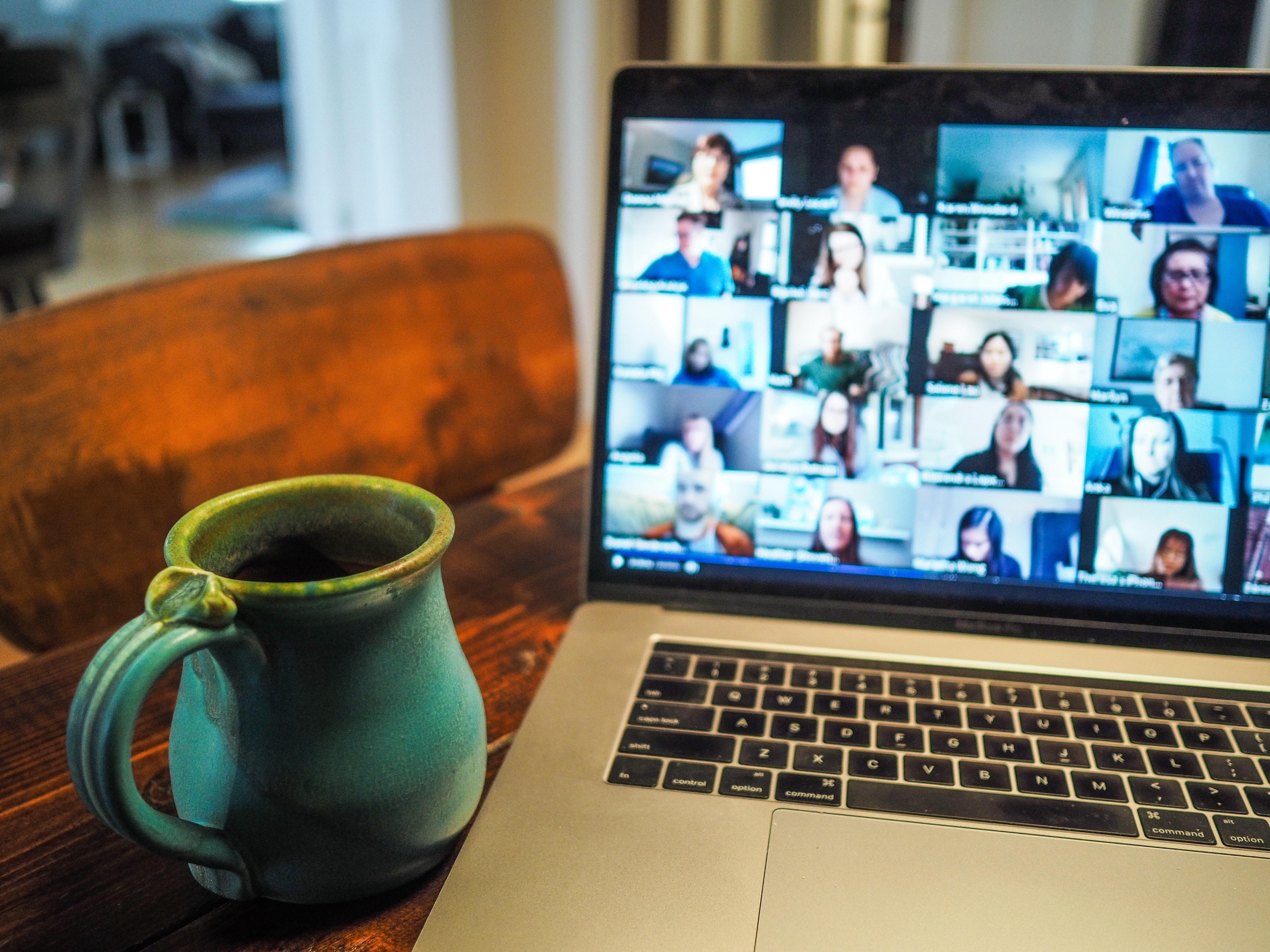 coffee mug and laptop with zoom conference on-screen